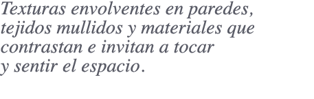 Texturas envolventes en paredes, tejidos mullidos y materiales que contrastan e invitan a tocar y sentir el espacio.